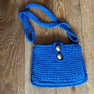 Blue crocheted shoulder bag with two gold buttons in the front
